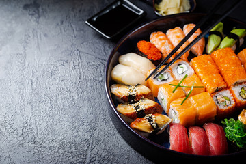 Wall Mural - Set of sushi and maki with soy sauce over black background. Top view with copy space