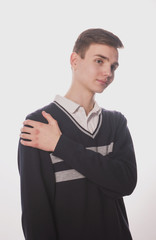 Wall Mural - Lifestyle photo of a young brown-haired man on a light background, a beautiful young guy in a shirt and sweater