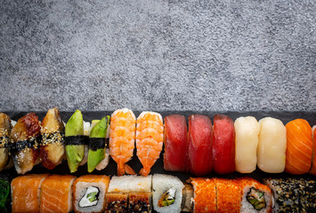 Wall Mural - Set of sushi and maki with soy sauce over stone gray background. Top view with copy space