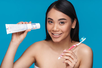 Poster - Smiling young woman holding toothbrush and paste.