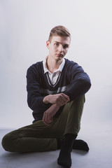 Wall Mural - Lifestyle photo of a young brown-haired man on a light background, a beautiful young guy in a shirt and sweater