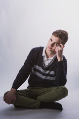 Wall Mural - Lifestyle photo of a young brown-haired man on a light background, a beautiful young guy in a shirt and sweater