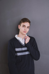 Wall Mural - Lifestyle photo of a young brown-haired man on a light background, a beautiful young guy in a shirt and sweater