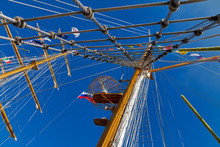 Mast Sailing Ship With Flags Of Russia And Other Countries Against The Blue Sky Perspective View From Below