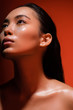 © LIGHTFIELD STUDIOS - low angle view of beautiful naked asian girl with silver sparkles on face on red