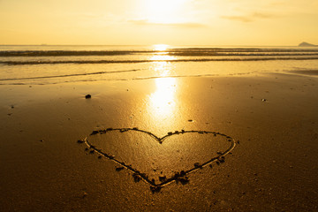 The heart in the sand while the sun is golden.