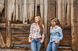 © MACO - Two western girls leaning on a barn and laughing. Bridger, Montana, USA