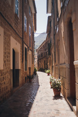 Naklejka na meble Valldemossa street, Mallorca island, Balearic Islands, Spain. Spanish cobbled narrow alleyway in between stone townhouses with wooden shutters