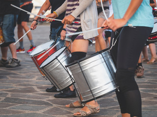 Toned photo of street musicians playing on drums on city street while celebrating carnival