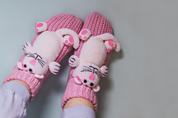 Legs of a girl in funny pink socks with cats in the blue background. Cozy slippers for the home.