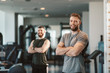 © djile - Two Handsome young man posing in a gym and looking at the camera with smile