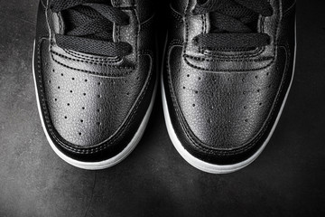 Black leather sports shoes close-up style. The concept of comfortable casual shoes. Dark background, minimalism, copyspace, top view, flat lay.