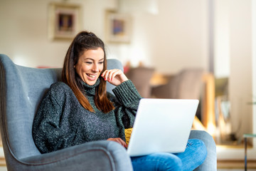 Happ young woman using notebook while working from home