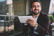 © BullRun - Cheerful Hispanic entrepreneur with tablet looking at camera