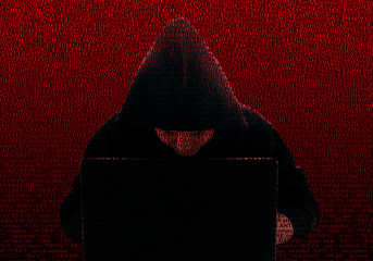 Wall Mural - Silhouette of a hacker in a black hood, against the background of computer technology terms. Concept: Theft of digital data, computer viruses, Internet security.