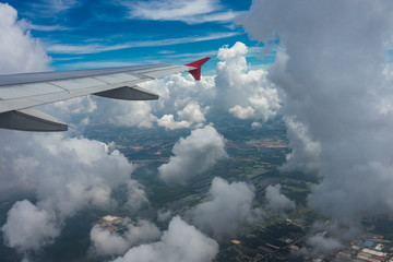 Photo from the window of an airplane. View from above on clouds and the earth. High. Sunny and cloudy day. Photo with telephone. View of the sky.