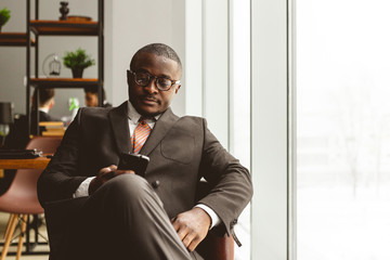 Portrait of a young successful businessman in a suit in the office. Close-up sitting in a chair by the window