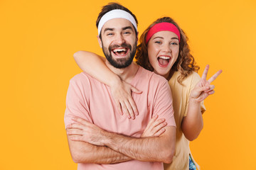 Wall Mural - Portrait of athletic young couple smiling and gesturing peace fingers