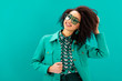 © LIGHTFIELD STUDIOS - smiling african american woman in jacket looking away isolated on turquoise