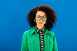 © LIGHTFIELD STUDIOS - stylish african american woman in jacket looking at camera isolated on blue