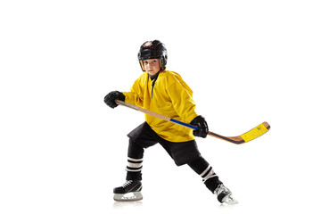 Little hockey player with the stick on ice court and white studio background. Sportsboy wearing equipment and helmet practicing, training. Concept of sport, healthy lifestyle, motion, movement, action