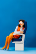 © LIGHTFIELD STUDIOS - african american with sleeping mask sitting on seat and sleeping on blue background