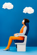 © LIGHTFIELD STUDIOS - side view of african american with sleeping mask sitting on seat and sleeping on blue background with clouds