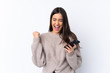 © luismolinero - Young brunette woman over isolated white background with phone in victory position