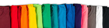 Wide Panorama Row Of Many Fresh New Fabric Cotton T-shirts In Colorful Rainbow Colors Isolated. Pile Of Various Colored Shirts White Background