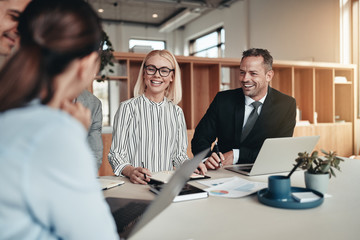 Laughing group of businesspeople working around an office table