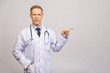 © denis_vermenko - Doctor senior man, medical professional pointing away side with finger isolated over grey background.