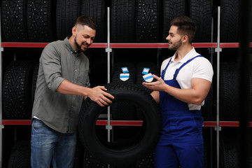 Canvas Print - Mechanic helping client to choose car tire in auto store