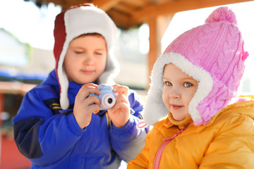 Poster - Little boy taking picture of girl outdoors. Future photographer