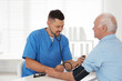 © New Africa - Doctor measuring blood pressure of senior patient in office