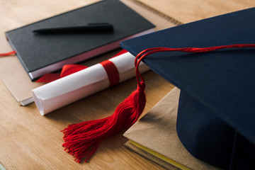 Poster - Selective focus of notebooks with pen, diploma and graduation cap on wooden background
