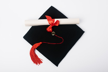 Wall Mural - Top view of black graduation cap with red tassel and diploma on white background