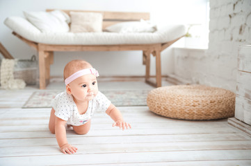 a small child sits on a sofa with a pallet. newborn baby girl in a living room in a rustic style clo