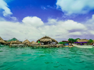 Ocean bar in Cholon beach. Tropical hut seats inside turquoise blue sea at the beach by Baru - Cartagena in Colombia