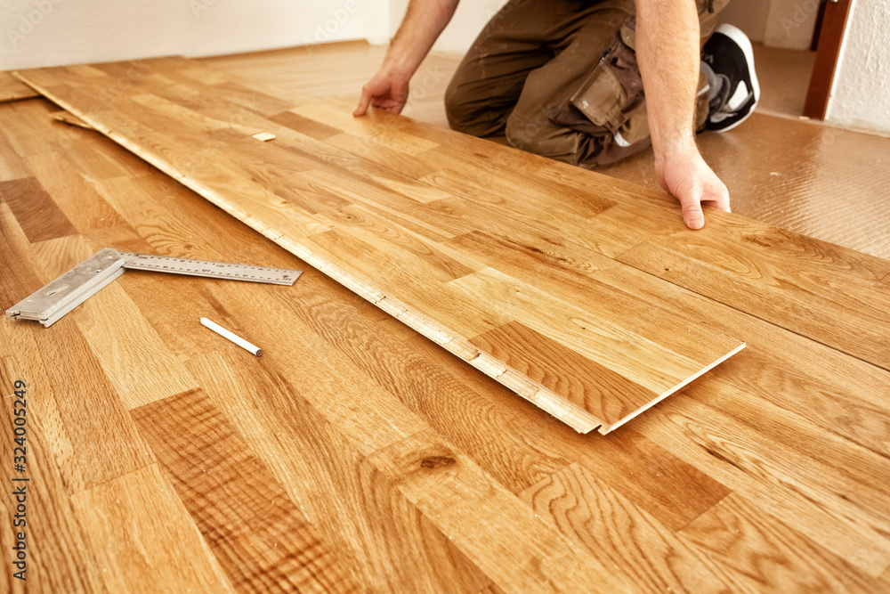 A craftsman lays oak parquet with a click system - obrazy, fototapety, plakaty 