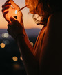 © Ekaitz Gerique/ADDICTIVE STOCK - Side view of cropped anonymous woman lighting cigarette with magnificent sunset on blurred background