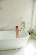 © Cavan Images - little toddler bathes in the bath naked