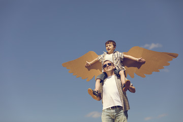 Father and son playing with cardboard toy wings