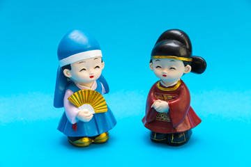 Decorative ceramic Korean figures, couple in traditional colorful clothes Han bock. Figures are allocated over a turquoise background. Collecting. Hobby and leisure.