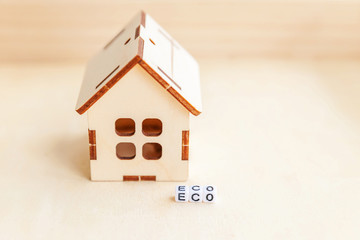 Miniature toy model house with inscription ECO letters word on wooden backdrop. Eco Village, abstract environmental background. Ecology zero waste social responsibility recycle bio home concept