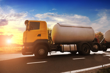 Canvas Print - Big metal fuel tanker truck shipping fuel on the countryside road against sky with sunset