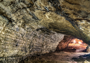 View inside the ancient cave with stone walls with additional lighting. Texture of a stone wall in a cave.