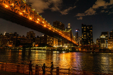 Canvas Print - People standing in front of a bridge at night