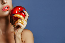 Close-up Of Beautiful Young Girl With A Smooth Tanned Skin Holding A Shiny Apple. Girl Biting Fresh Red Honey Apple Over Blue Background. Healthy Eating. Fruits And Vegetables.