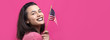 Happy young woman holding American flag against a studio pink background