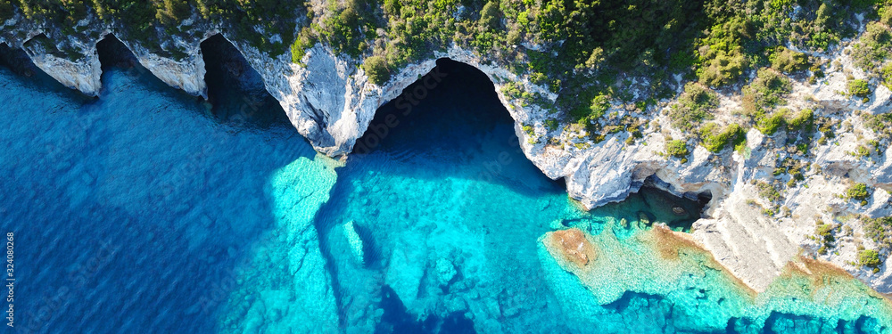 Aerial drone ultra wide photo of tropical white rocky bay of blue lagoon with turquoise clear waters, white volcanic caves and sail boats docked, island of Paxos, Ionian, Greece - obrazy, fototapety, plakaty 